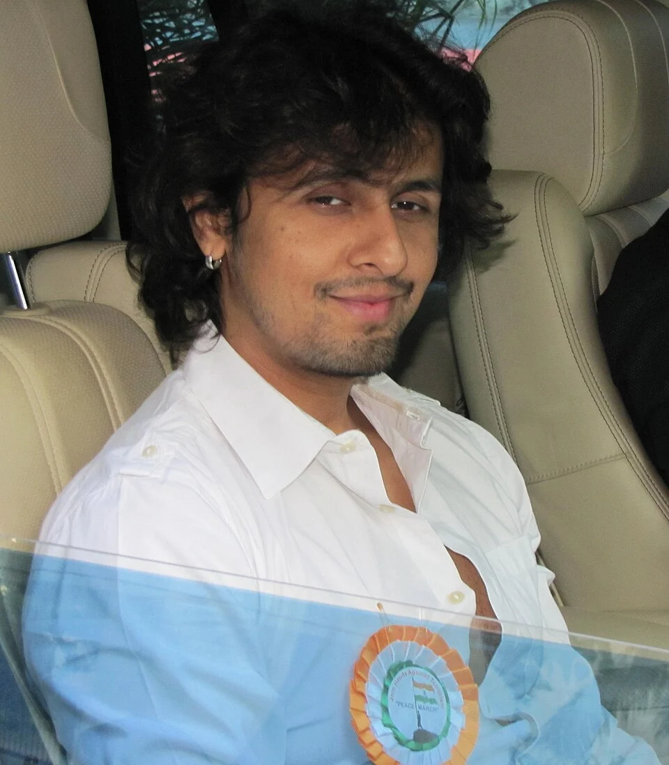 Sonu Nigam seated in a car during a 2011 peace rally, with window reflections and his badge retained
