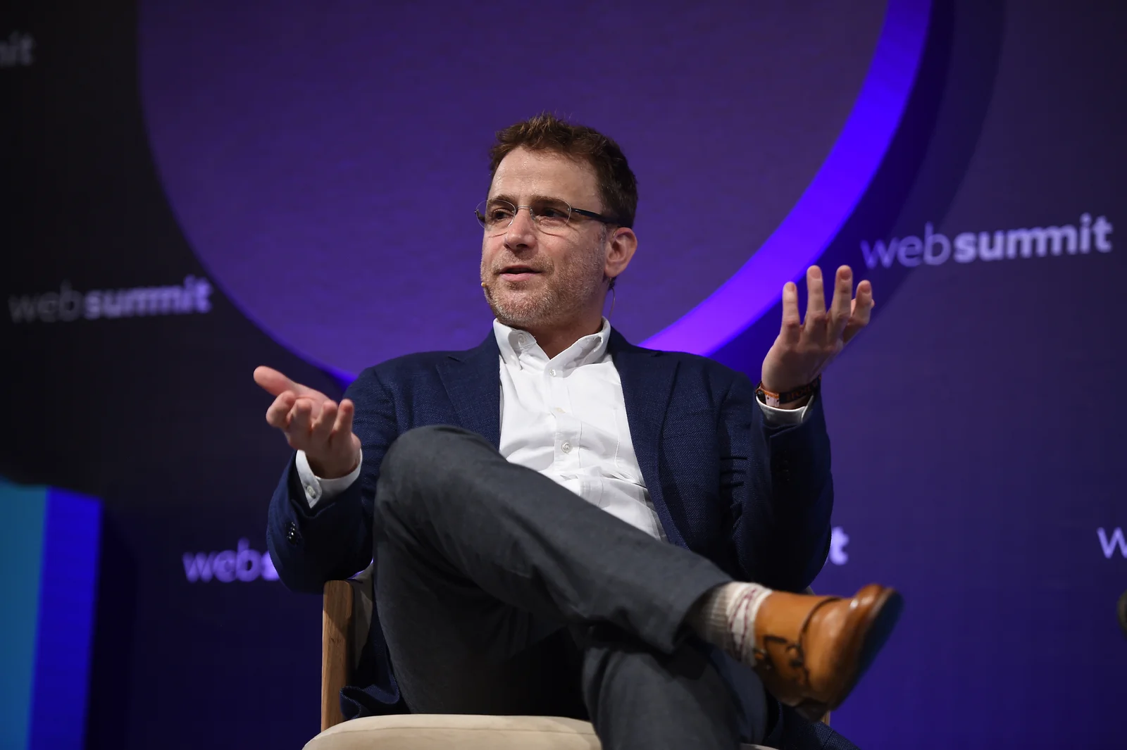 Stewart Butterfield seated on stage with his hands raised at Web Summit in Lisbon in November 2017, in the complete supplied photograph.