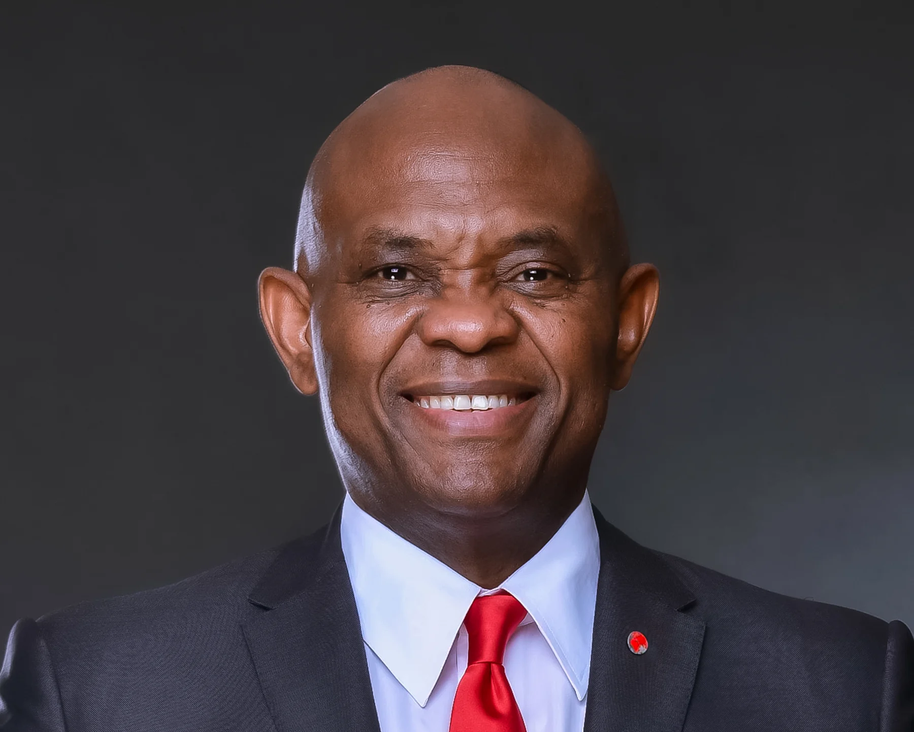 Tony Elumelu smiling in a dark suit, with the complete supplied Heirs Holdings portrait retained.