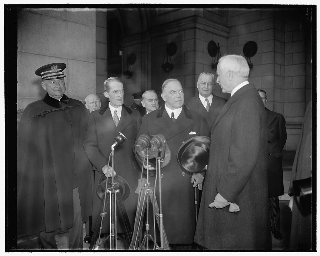 Mackenzie King in the centre foreground holding a hat beside Cordell Hull, with officials and other men at Washington Union Station in November 1938; the entire archive frame is retained.
