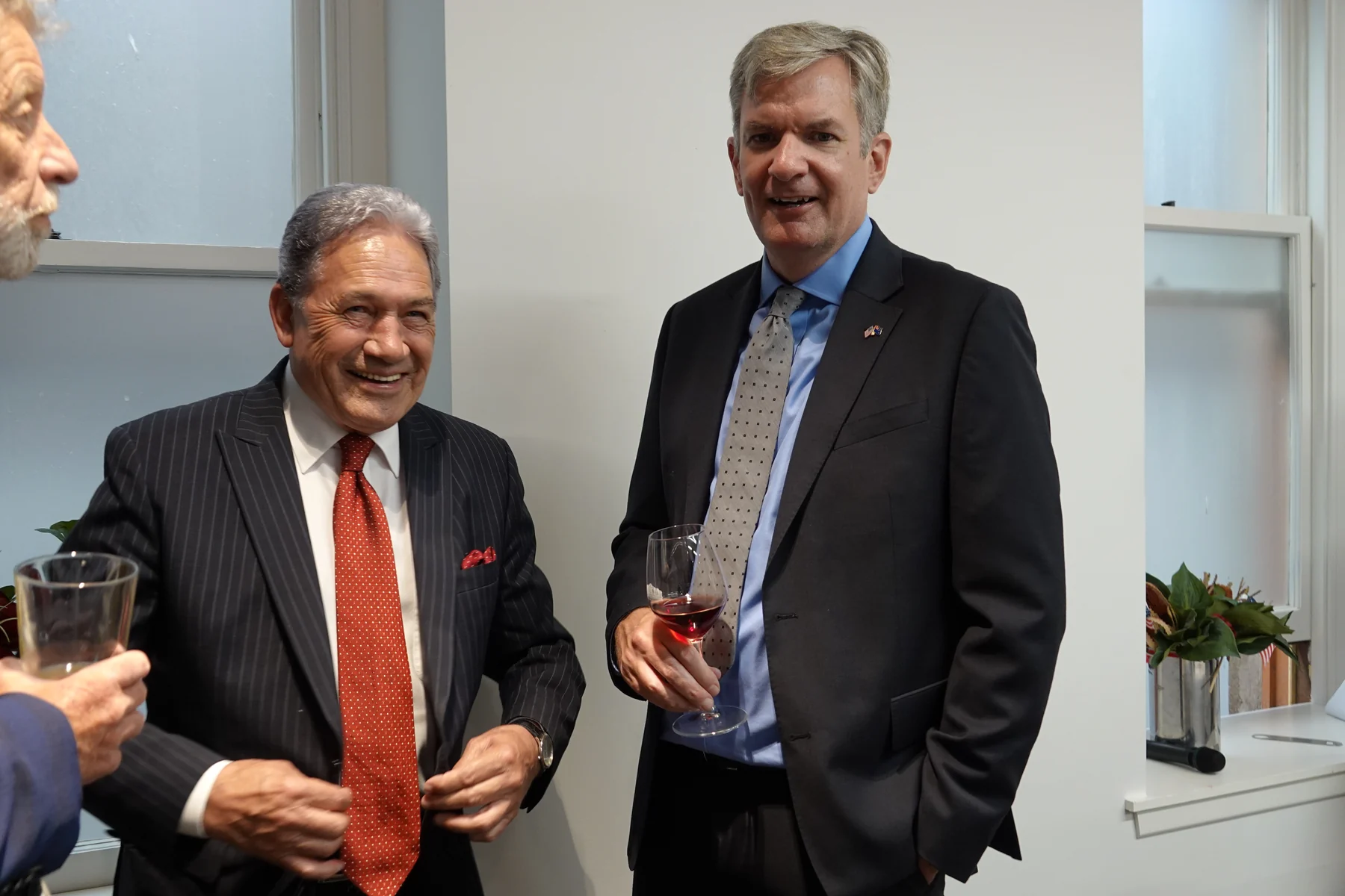 Winston Peters at left in a pinstriped suit and red tie at a US Embassy New Zealand gathering on 30 January 2024.